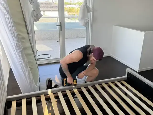 Safepack removalist reassembling a bed frame in a bedroom after a move