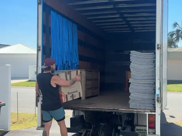 Safepack removalist carrying a box from the back of the removal truck