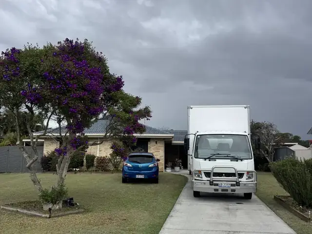 Front of a Safepack removal truck parked on a driveway under a jacaranda tree